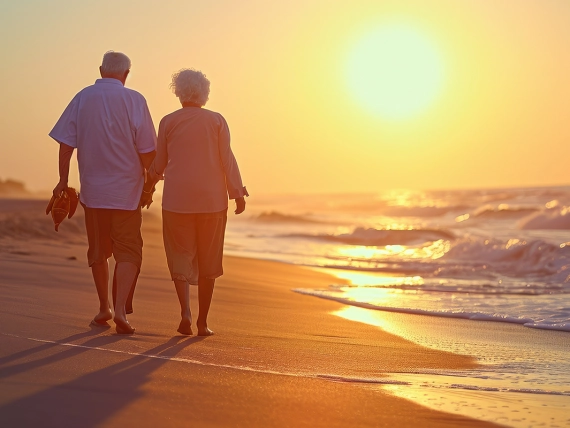 A joyful elderly couple walking on the beach enjoying a leisurely sunset