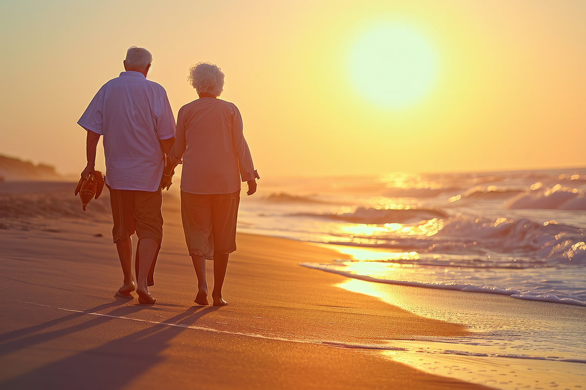 A joyful elderly couple walking on the beach enjoying a leisurely sunset