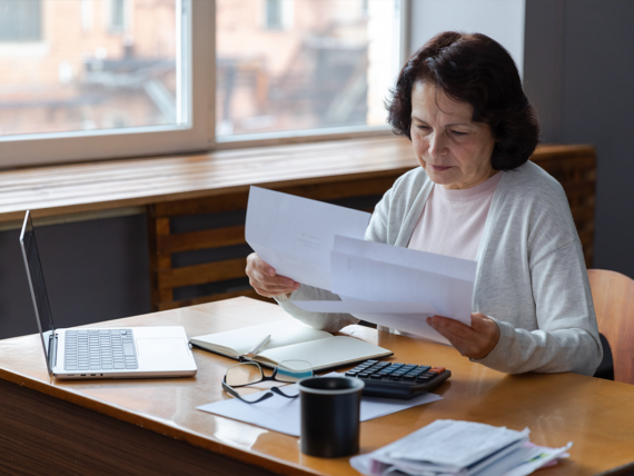 Older woman sitting at desk looking over paperwork