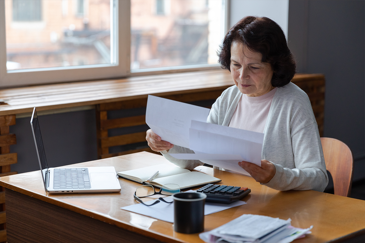 Older woman sitting at desk looking over paperwork